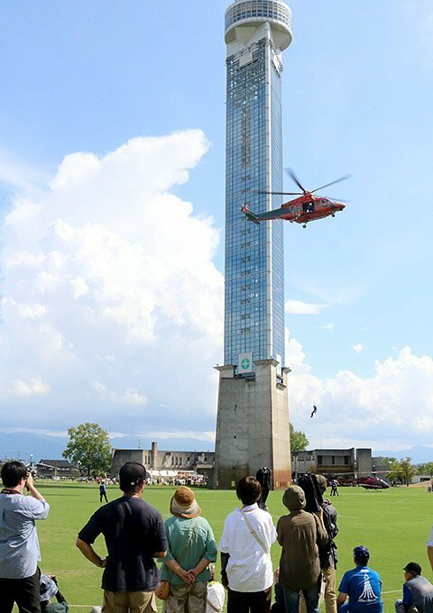 クロスランドタワーのそばで救助訓練を行う県消防防災ヘリ「とやま」