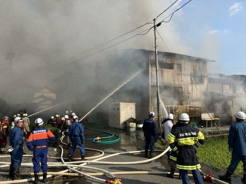 燃えて煙を上げる工場＝24日午後3時50分、岡山市北区建部町下神目