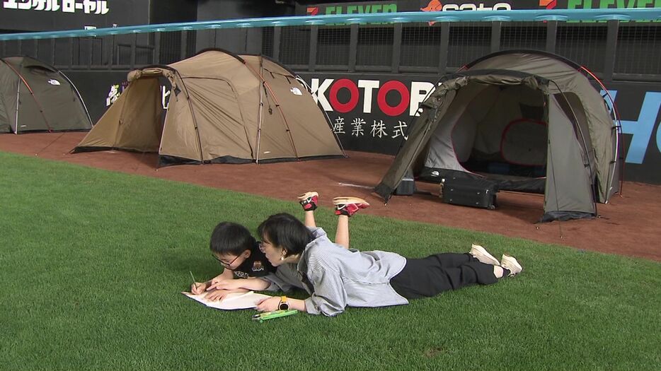 芝生の上で夏休みの宿題をする子どもも