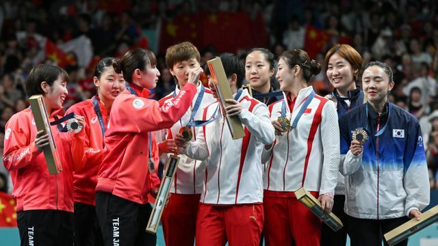 女子団体戦の表彰式で早田ひな選手が中国の孫穎莎選手の頭についたゴミをとる(写真：AFP＝時事)