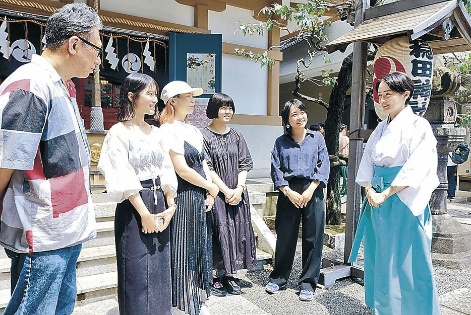 船田宮司（右）から穏田神社について説明を受ける金沢美大生＝都内