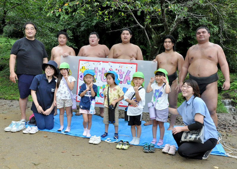 園児と記念写真に納まる安治川親方（後列左）と力士たち