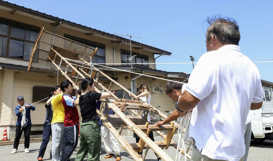 能登半島地震で被災した石川県輪島市町野町で、祭りに向けて巨大な灯籠「キリコ」を準備する住民や学生ら＝6日午前