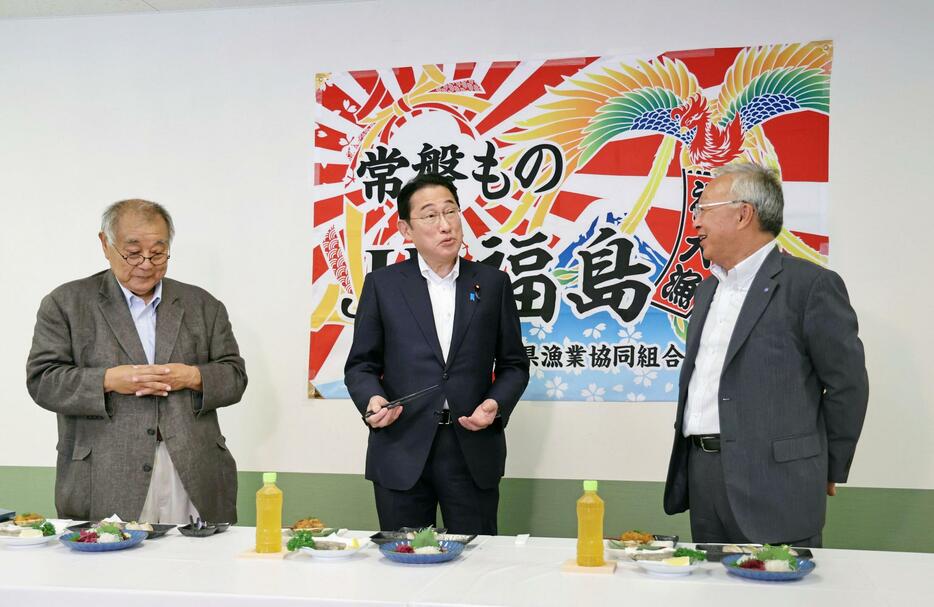 食堂で海産物などを試食する岸田首相。左は福島県漁連の野崎哲会長＝24日午後、福島県いわき市の小名浜魚市場（代表撮影）