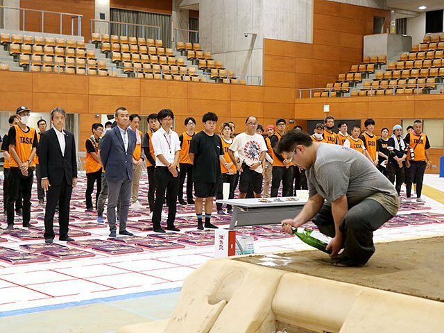 土俵の隅に酒を振りかける呼び出し（手前）＝県西部体育センター