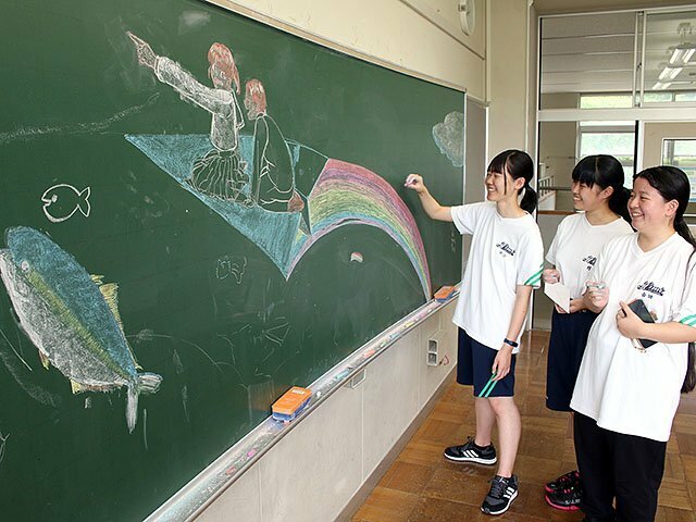 黒板にチョークで絵を描く氷見高校の生徒＝久目地区交流館