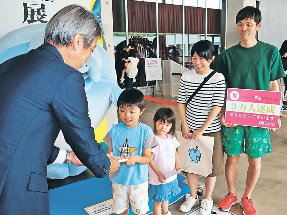 ３万人目の来場者となった石崎奏汰さん（左から２人目）と家族ら＝氷見市芸術文化館