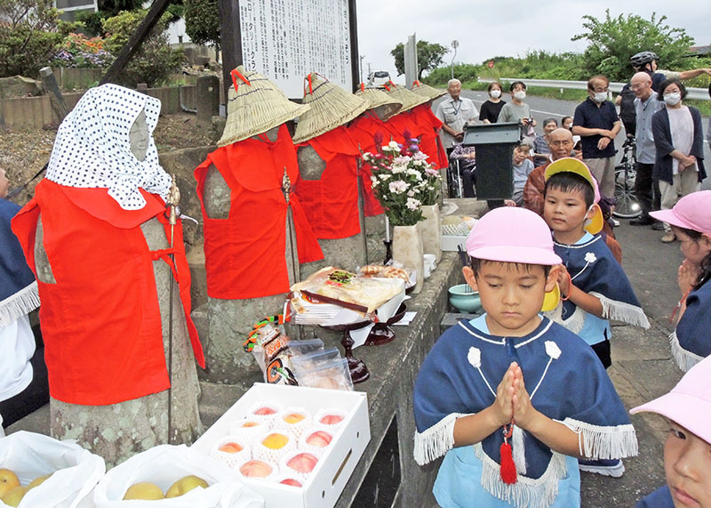 真新しい編みがさや衣装をまとった地蔵に手を合わせて参拝するはなほこども園の年長児