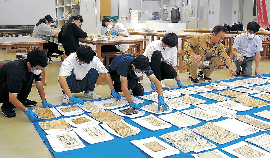 文書を床に並べて乾燥させる学生＝金沢学院大