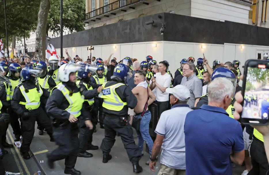 7月31日、ロンドンの首相官邸前で衝突する反不法移民のデモ参加者と警察官（共同）