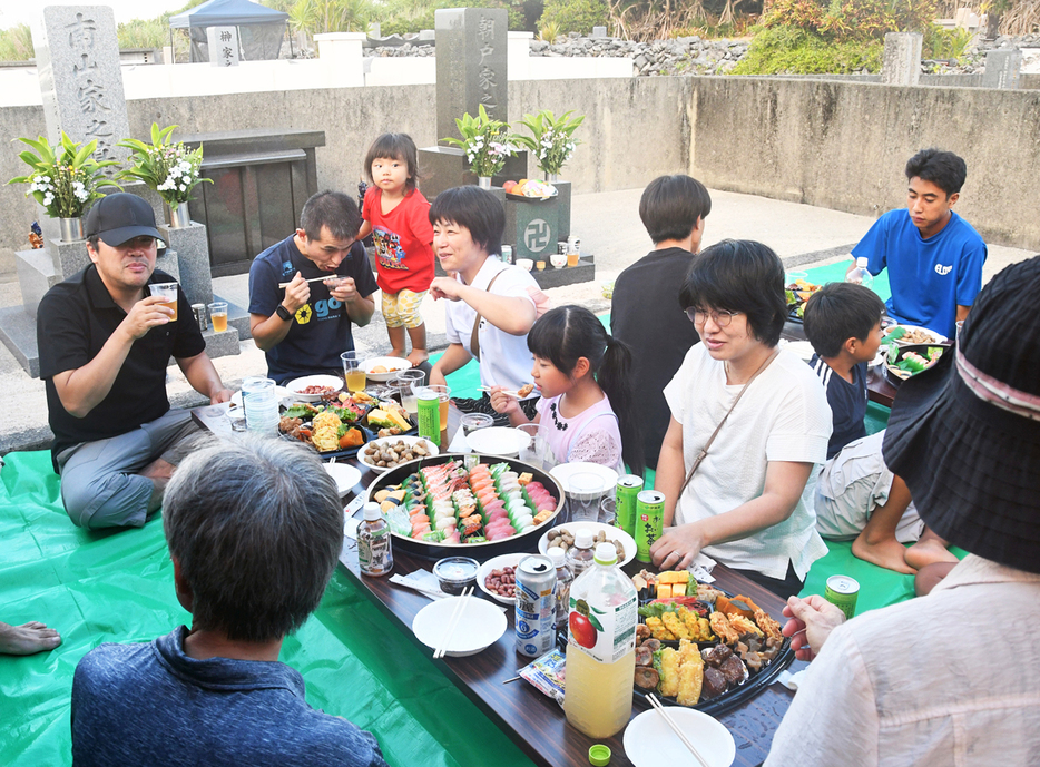 墓前に集い、先祖の霊を慰める親族ら＝15日、鹿児島県知名町瀬利覚