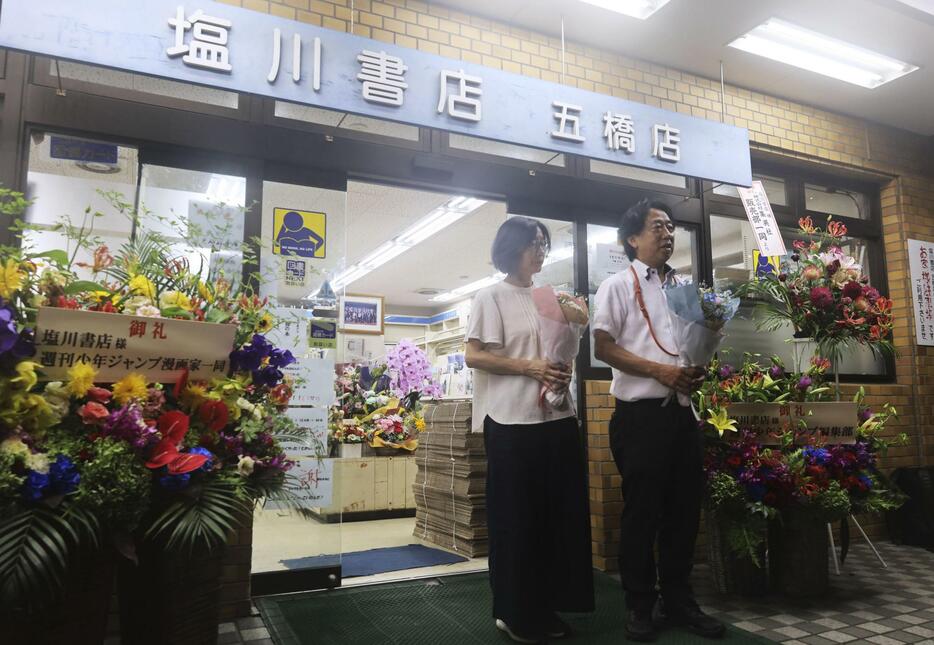 「塩川書店五橋店」の最終日の営業を終え、常連客らにあいさつする店主の塩川祐一さん（右）＝31日夜、仙台市