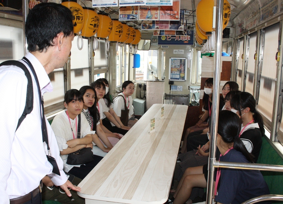 ビール電車の車内を案内される高校生=豊橋鉄道赤岩口車庫で