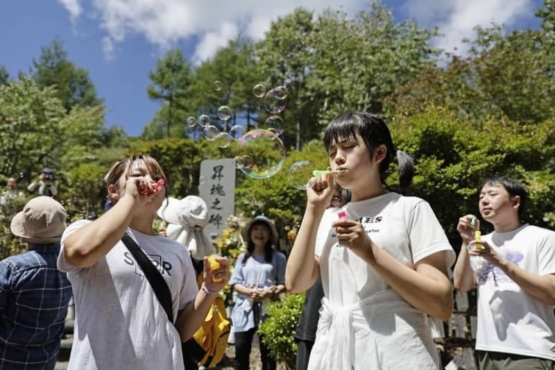 「昇魂之碑」の前でシャボン玉を飛ばす人たち＝２０２４年８月１２日