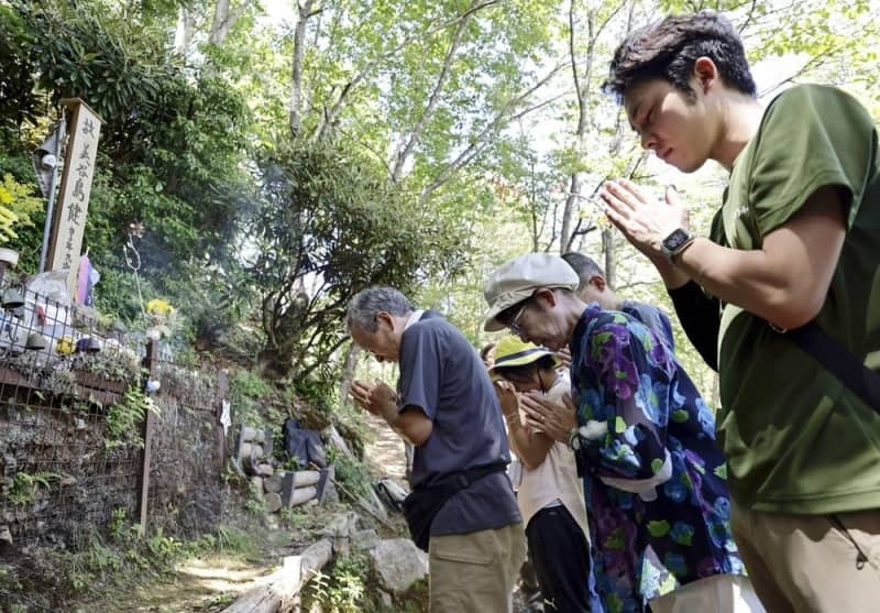 事故で亡くなった次男の墓標に手を合わせる「８・１２連絡会」事務局長の美谷島邦子さん（右から２人目）ら＝２０２４年８月１２日、群馬県上野村