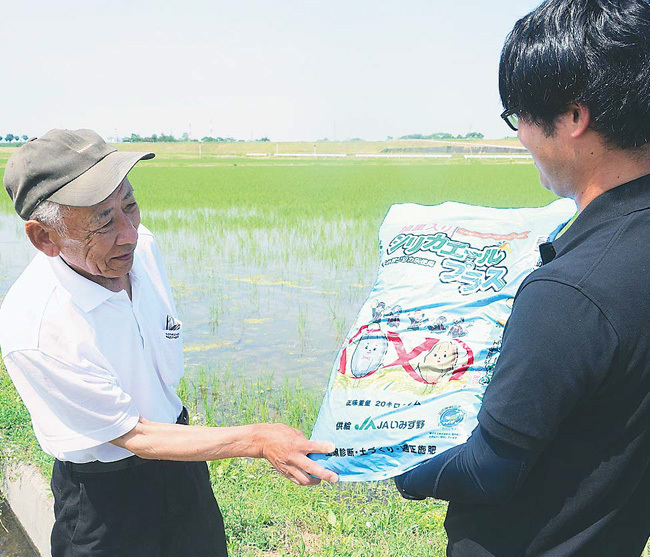 JA職員ともみ殻由来の土壌改良資材の効果について意見を交わす夏野さん（左）（富山県射水市で）