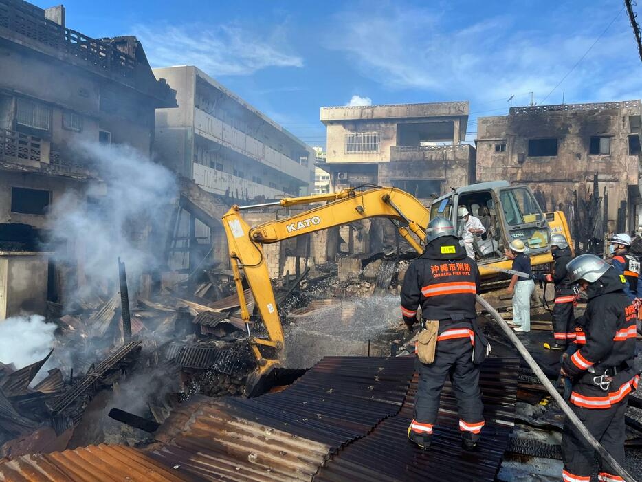 がれきの表層を取り除きながら消火活動する消防隊員ら＝19日午前8時半すぎ、沖縄市