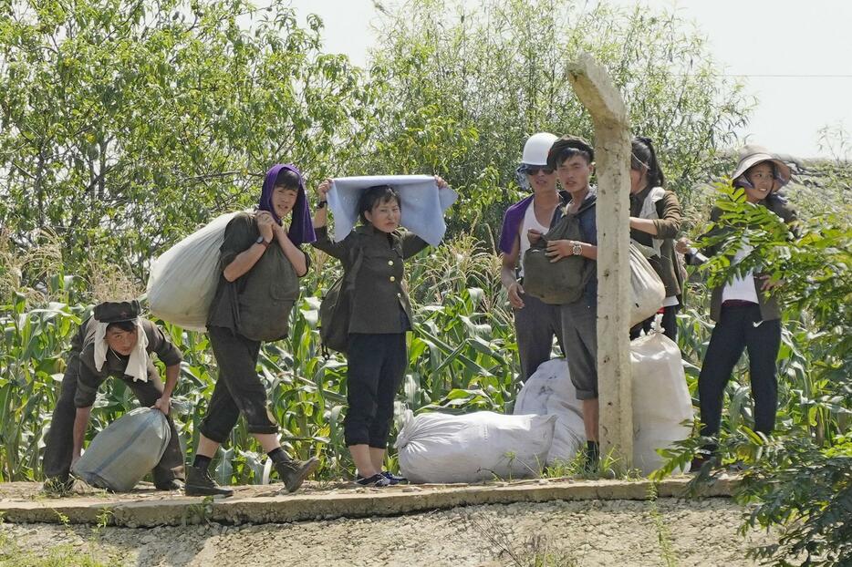 大規模な洪水で被災した北朝鮮新義州の「将軍楼」で荷物を運ぶ人たち＝14日、中国・丹東から撮影（共同）