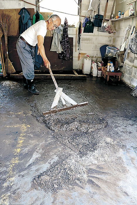 車庫に流れ込んだ泥をかき出す住民＝２６日午後２時１５分、上市町釈泉寺