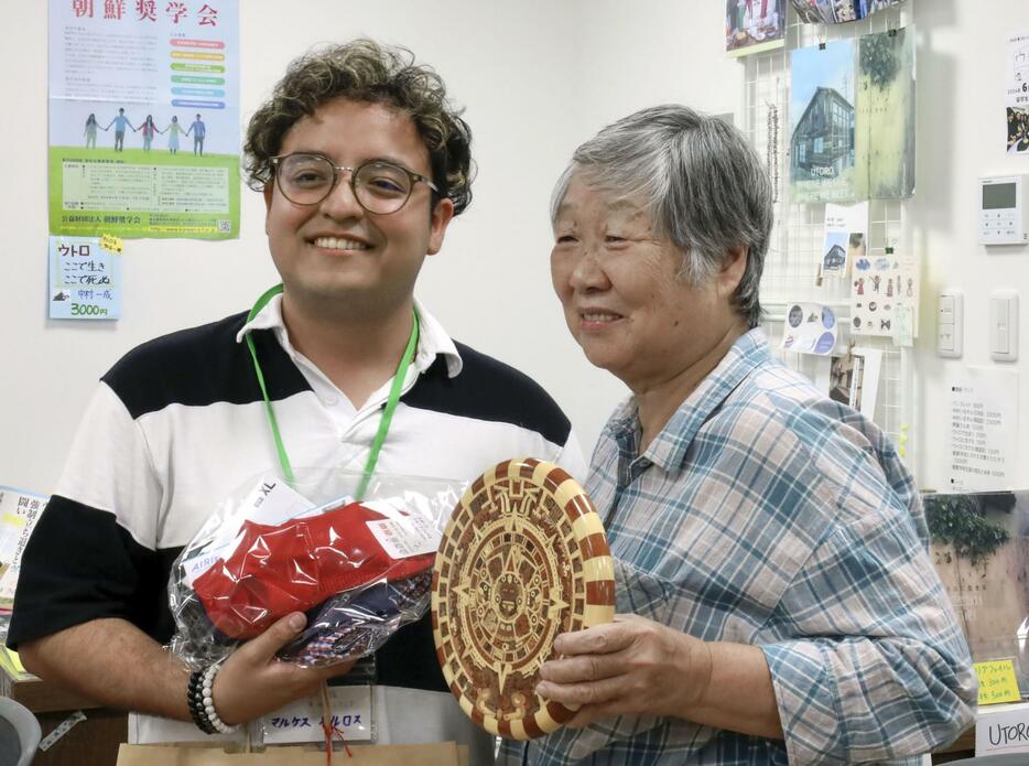 ウトロ地区の住民と贈り物を交換し合うカルロス・マルケスさん（左）＝京都府宇治市のウトロ平和祈念館