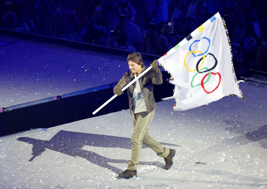 パリ五輪の閉会式に登場し、五輪旗を掲げるトム・クルーズさん＝11日、パリ郊外（共同）