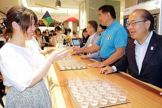 オープニングイベントで地酒を振る舞う新田知事（右）ら＝大阪市の「ＨＯＫＵＲＩＫＵ＋（ホクリクプラス）」