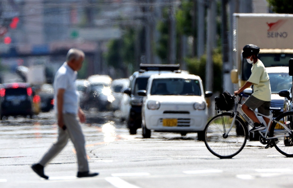 猛暑でかげろうや逃げ水が現れる中、交差点を歩く人たち（8日午後2時39分、山口市中央）