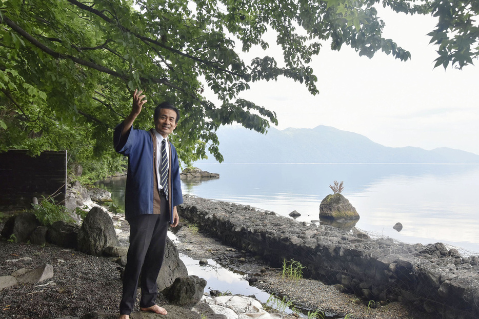 支笏湖（右）の前で旅館再建の手応えについて話す日生下和夫社長＝北海道千歳市