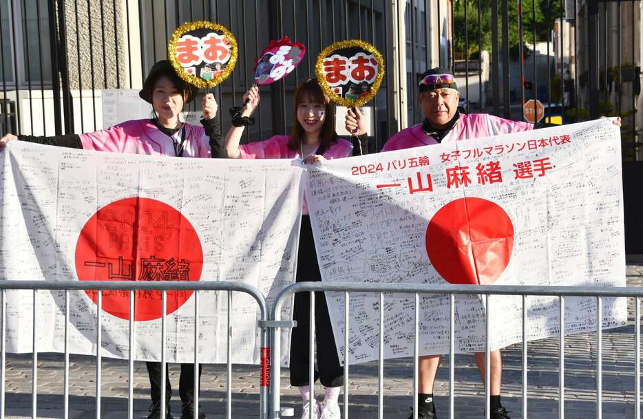 出水をはじめ鹿児島県内の高校生が寄せ書きした日の丸を手に一山麻緒に声援を送った父剛さん（右）ら家族＝１１日、フランス