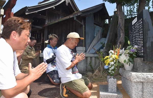 事故現場近くに移設した伝承碑に手を合わせる実行委のメンバーたち