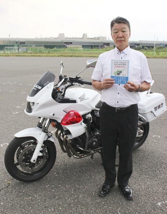 著書「ライダーのための基本の乗車姿勢7つのポイント」を手にする警視庁白バイ訓練所の元教官竹原伸さん＝7月31日、東京都世田谷区