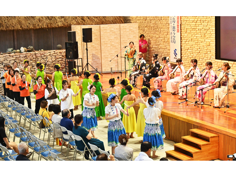 奄美芸能島唄研究会の演奏に合わせて踊る「シマジマだより喜界島」の出演者ら＝17日、鹿児島県奄美市笠利町