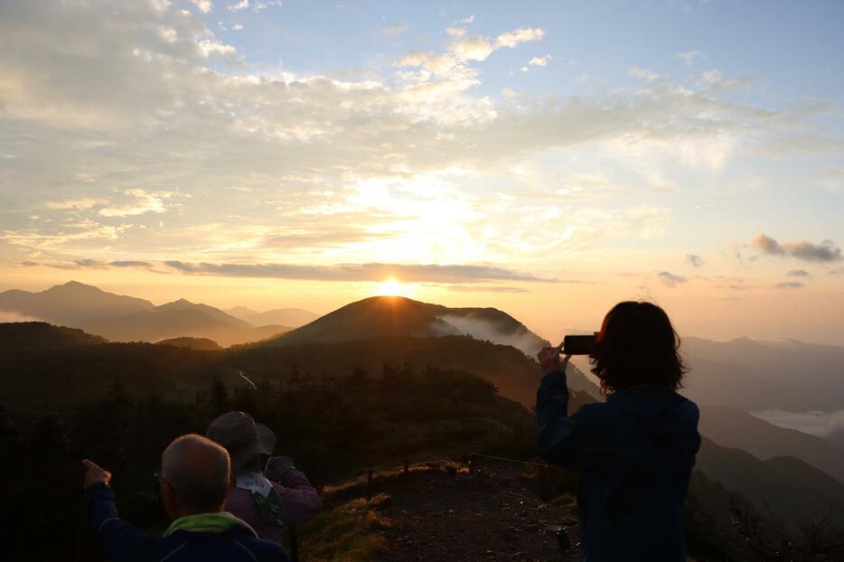 周辺を覆っていたガスが晴れ、束の間見えた御来光を写真撮影する登山者ら＝6日午前5時18分、南アルプス光岳山頂付近