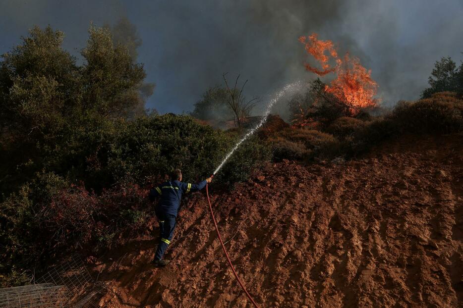 ギリシャの首都アテネ近郊で、山火事の消火に当たる消防士＝12日（ロイター＝共同）