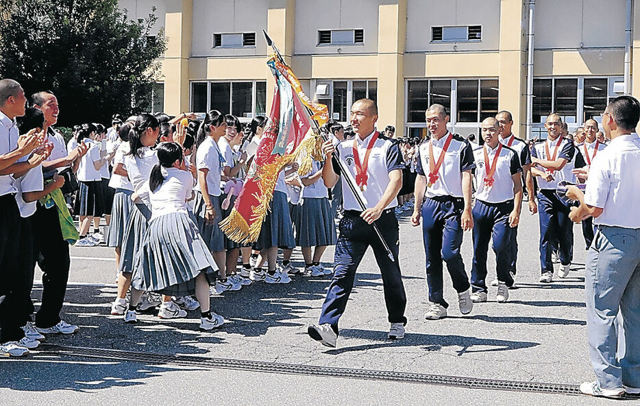 生徒からエールを受け、行進する野球部員＝富山商高