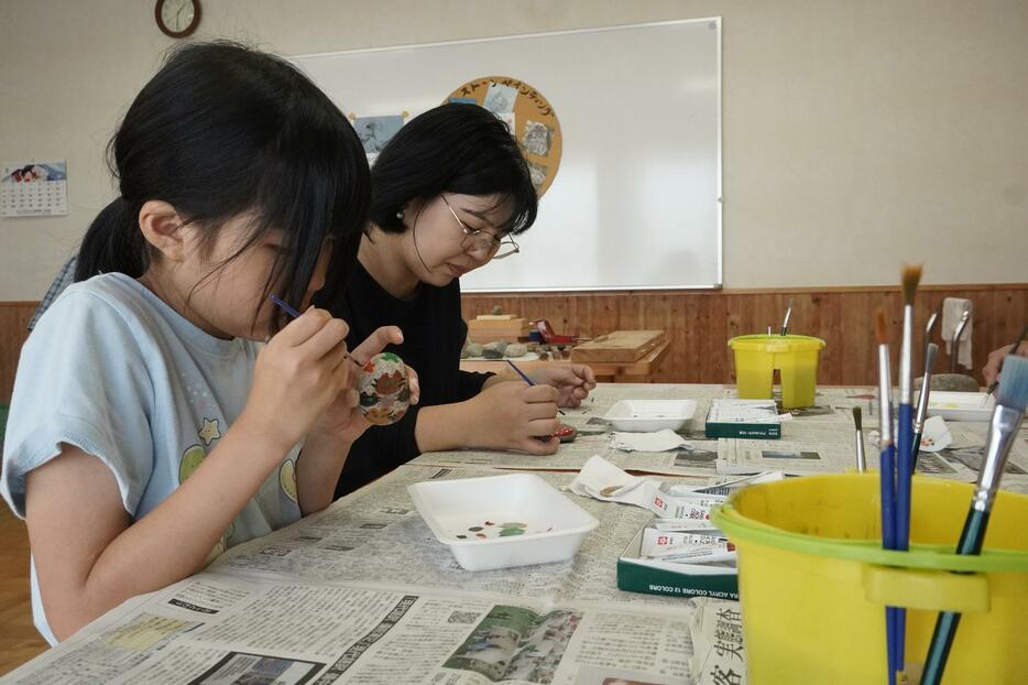 選んだ石に思い思いの絵を描く参加者=岡山県津山市で