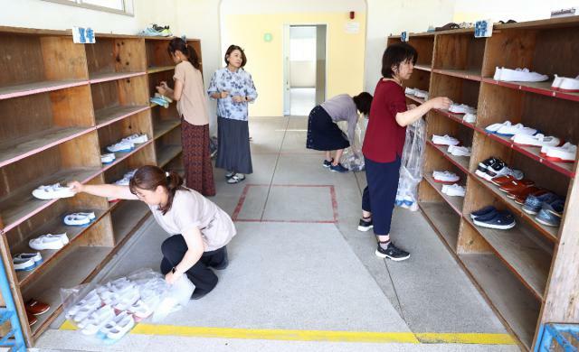 児童の上履きを靴箱から校舎内に片付ける教諭ら＝２７日午後、宮崎市・青島小学校