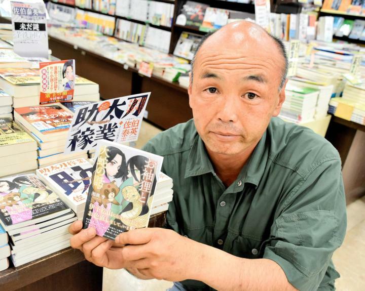 自費出版した「お袖狸と大蛇の話」を書店で手にする松岡さん