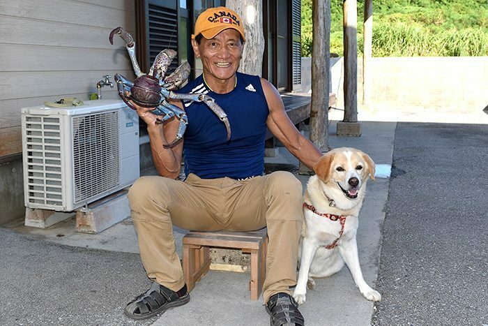 巨大ヤシガニを捕まえた當真嗣満さんと愛犬ハッチ－＝8月1日、うるま市勝連平安名