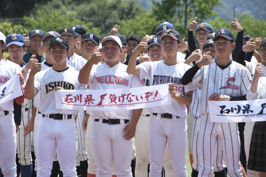 「石川県負けないぞ！」と書かれたタオルを掲げる宮城県高野連選抜の選手たち