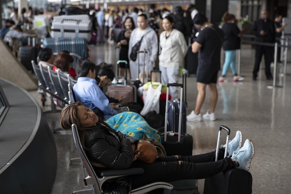 7月19日、米首都ワシントン・ダレス国際空港でフライトの再開を待ちながら休む乗客＝（ゲッティ＝共同）