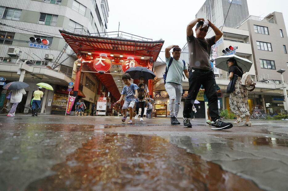 雨の中、名古屋市の繁華街・大須を歩く人たち＝31日午後