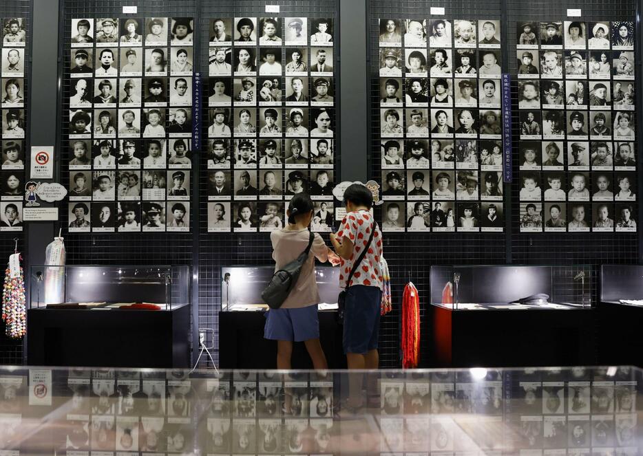 学童疎開船「対馬丸」の撃沈から80年となり、学童らの遺影が掲示された対馬丸記念館を訪れた子どもたち＝22日午前、那覇市