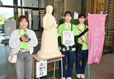 「平和の灯」（中央）と一緒に写真におさまる県医療センター好生館看護学院の学生たち=佐賀市兵庫南