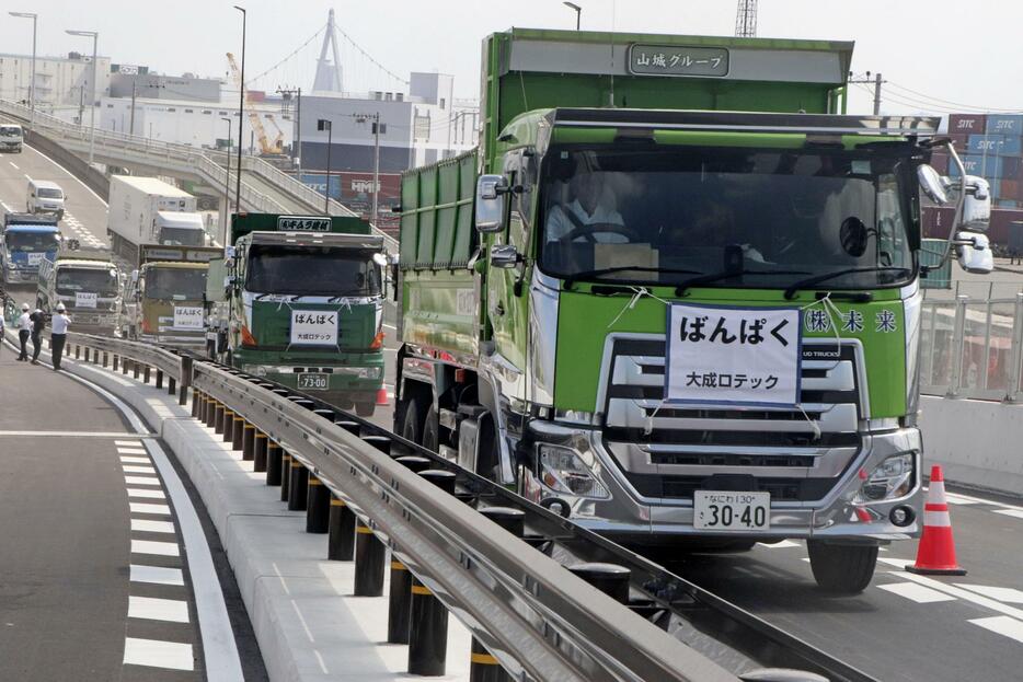 開通した高架橋を通り、万博会場に入る工事車両＝1日午前、大阪市