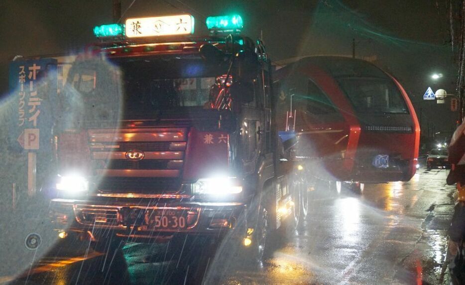 大雨の中陸送を開始。東大阪市の近畿車両から八尾市の高安車庫へ＝25日午前2時すぎ、大阪府東大阪市で