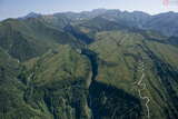 落差350mは日本一と言われる称名滝。画面右手には立山アルペンルートの立山有料道路が通り、画面上方の弥陀ヶ原、室堂平へと続く。背後の峻険を越えてこのダイナミックな地形を過ぎた先の谷間に立山砂防軌道がある（2013年9月18日、吉永陽一撮影）。