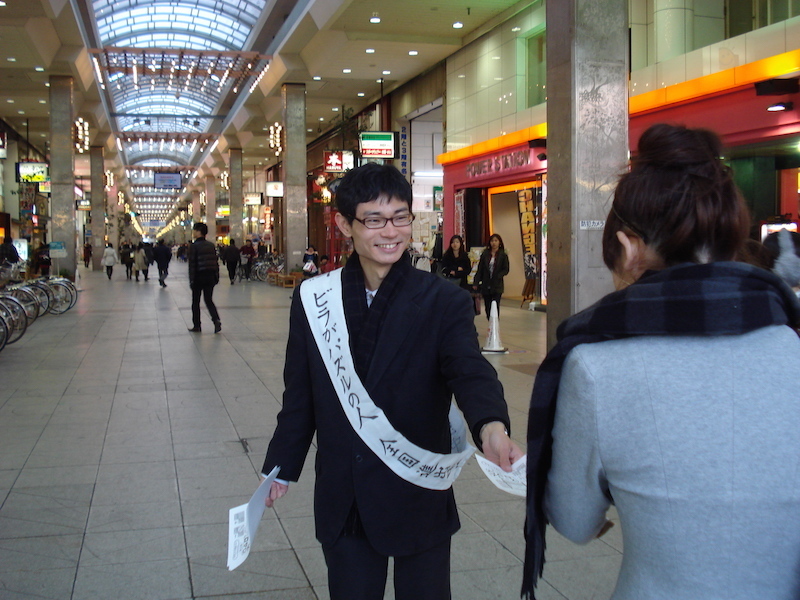 「ビラがパズルになってます」と声をかけ、道行く人にパズルのビラを配る東田さん（愛媛県松山市）