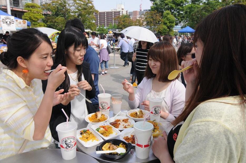 [写真]友達と来場した女子グループ。パエリアを頬張りながら、おしゃべりに花が咲く