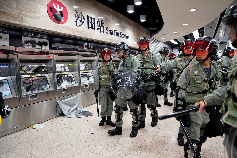 [写真]2019年9月22日、香港の沙田駅構内を棍棒を持って巡視する警察（ロイター/アフロ）